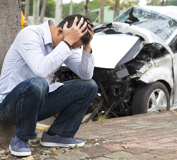 car accident lawyers Immediately after a car crash, a man with confusion is sitting in the pathway with hands-on his heads